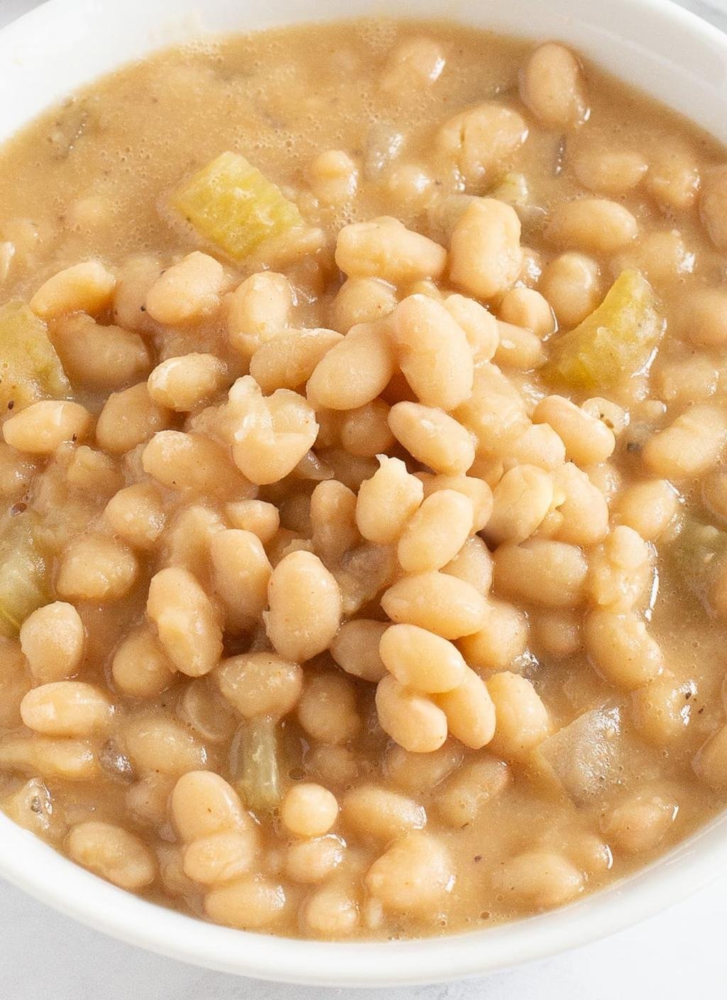 Creamy white bean dish in a light brown sauce with small vegetable chunks in a bowl (informational).