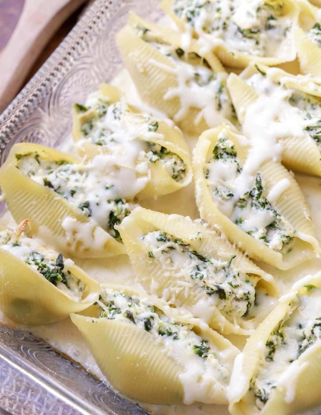 Shell pasta stuffed with spinach and ricotta in a creamy sauce on a decorative tray