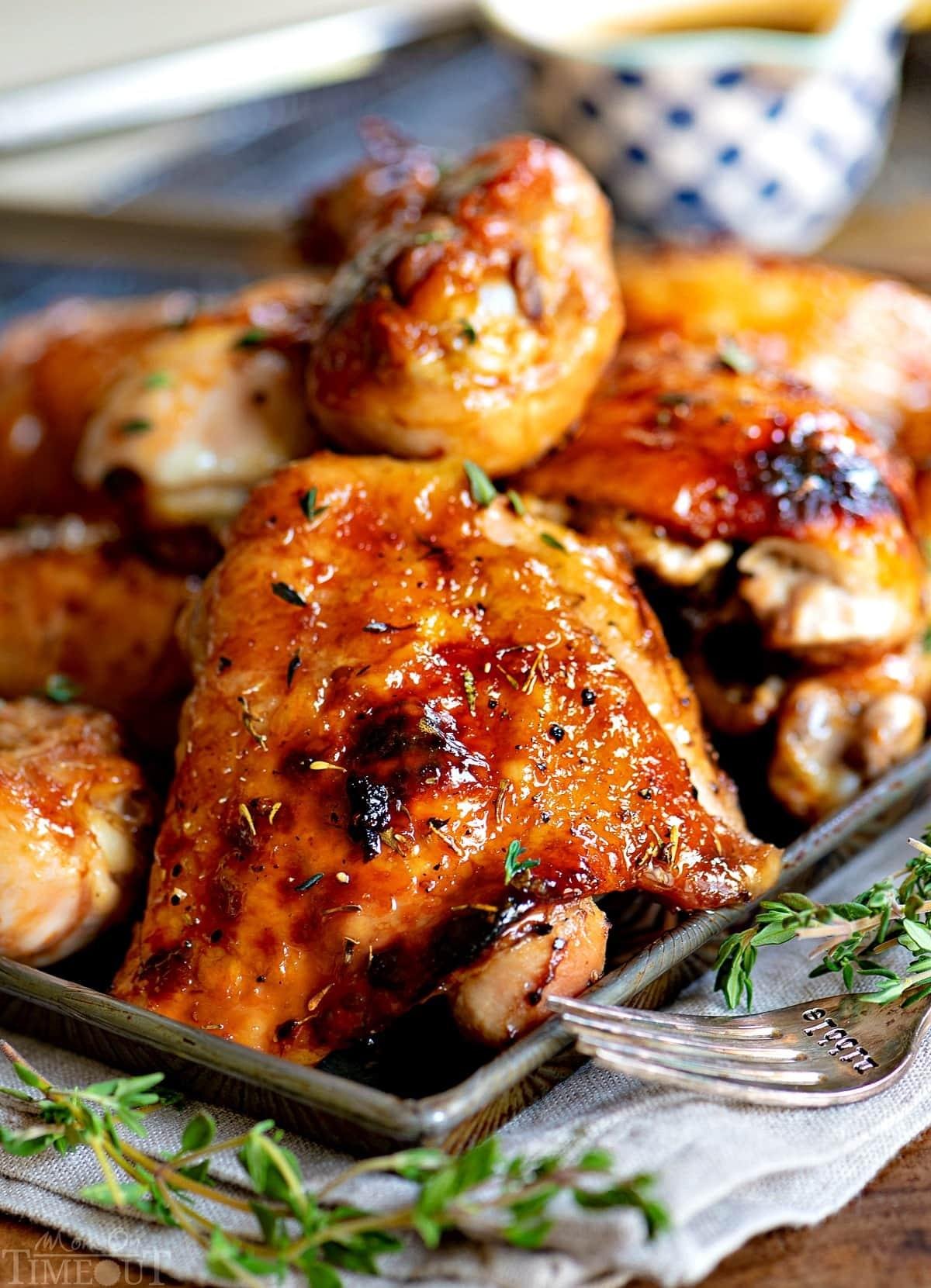 Juicy roasted chicken pieces with a caramelized glaze and thyme sprigs on a baking tray.