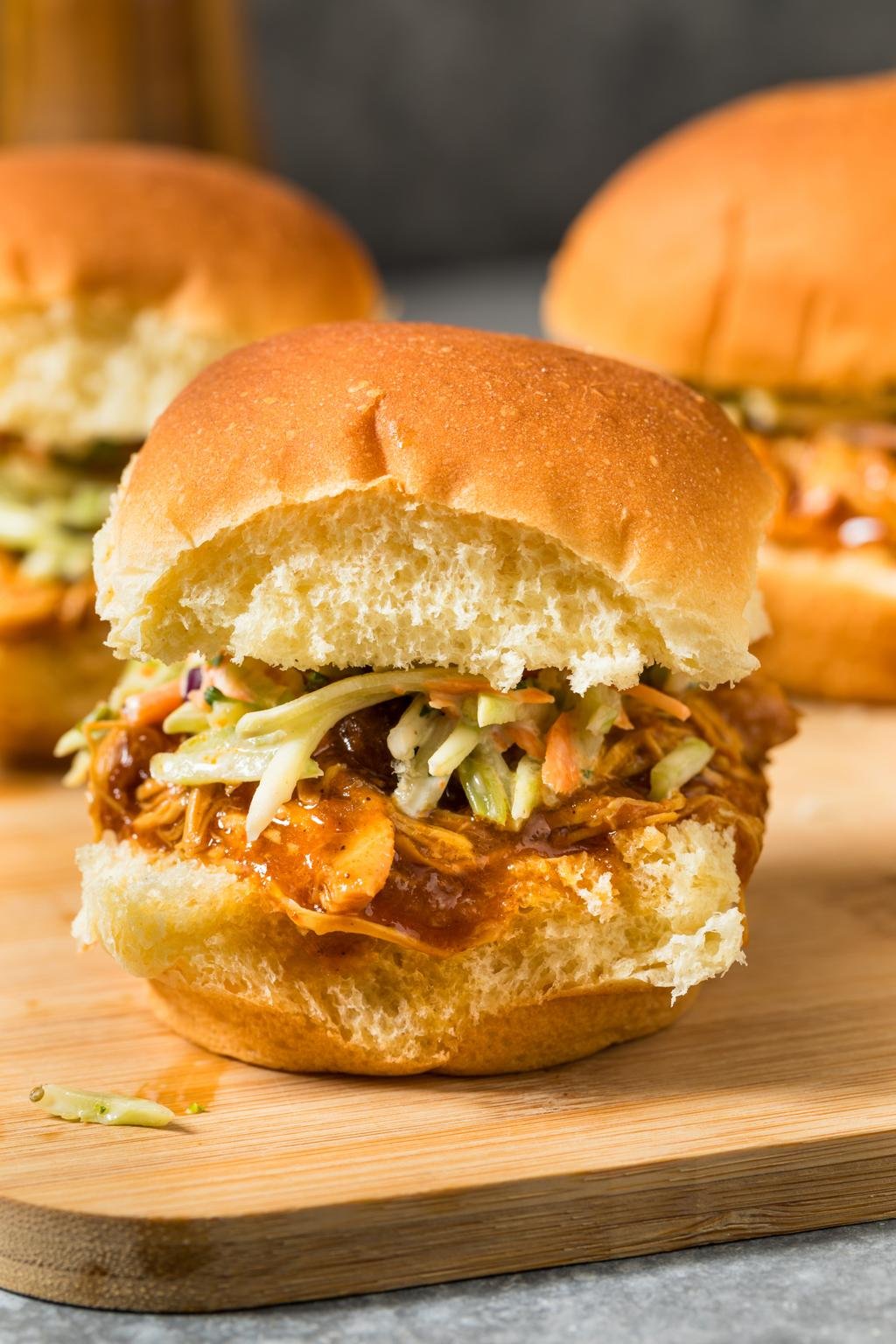 Barbecue pulled pork sandwich with coleslaw on a toasted bun, on a wooden board