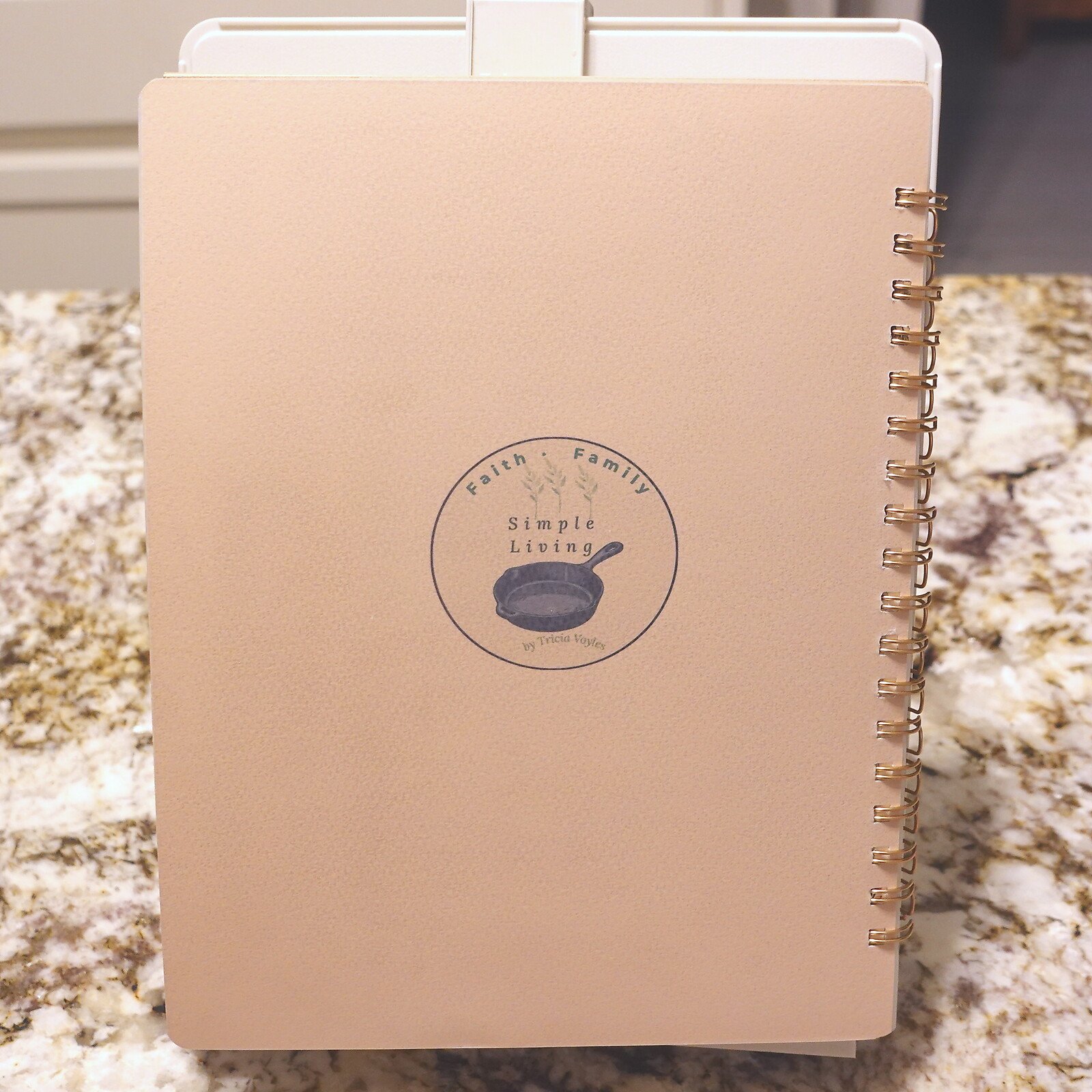 11-back-cover - Simple Living Faith Pink spiral-bound notebook with a circular logo reading 'Faith • Family' and 'Simple Living' with a small frying pan illustration on the front cover.