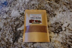 Bag labeled Simple Living Faith Harvest Chili Blend on a speckled granite countertop.