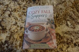 DSC00238 - Simple Living Faith Cozy Fall Suppers cookbook cover on a granite countertop with the title and a soup photo on the lower half